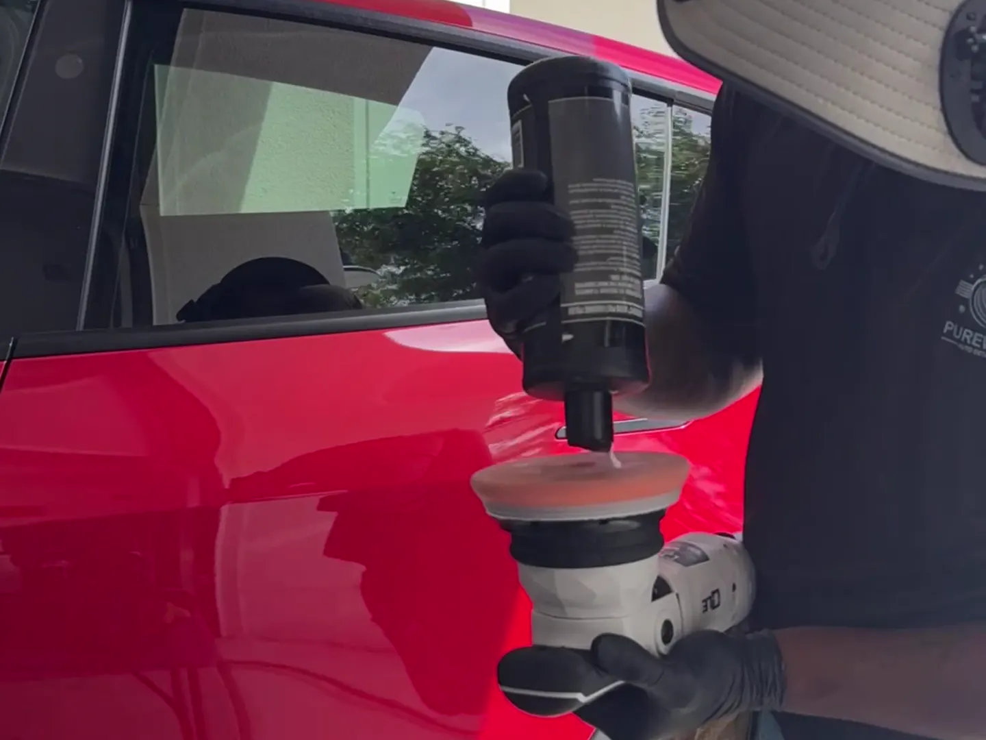 Pure Wave technician machine polishing a red Tesla Model Y during paint correction
